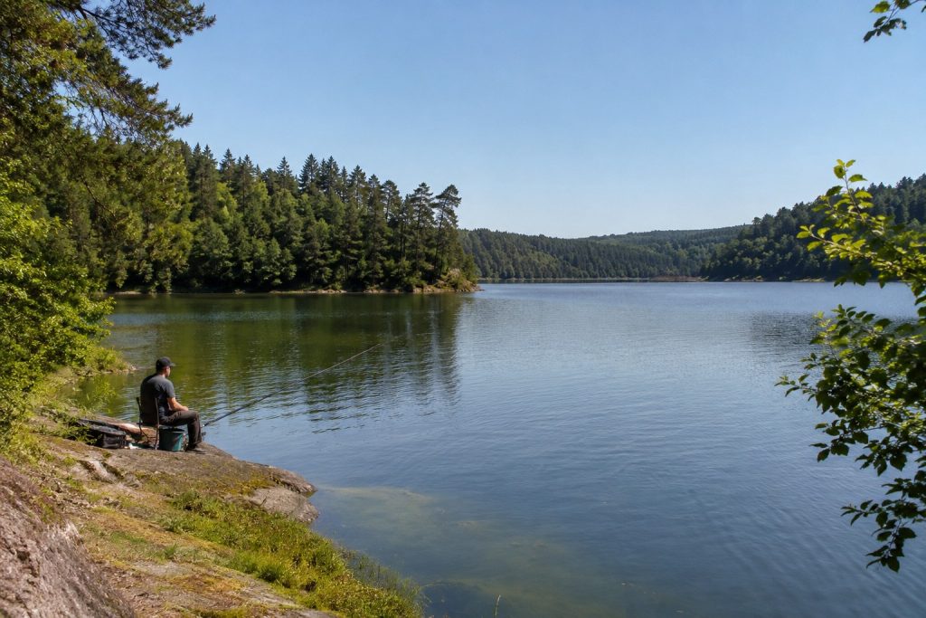 Pêcheur installé sur les rives du lac d'Éguzon dans un environnement naturel préservé de la Creuse
